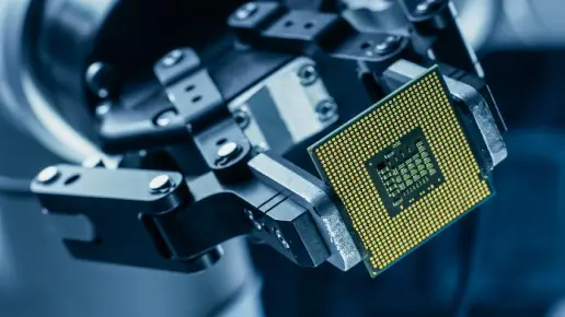 Close up shot of a processor chip being held by a robotic manufacturing arm.